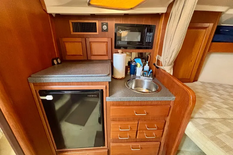  Yacht Photos Pics Compact kitchen area in a 2002 Luhrs 32 Open boat with sink, microwave, and mini fridge.