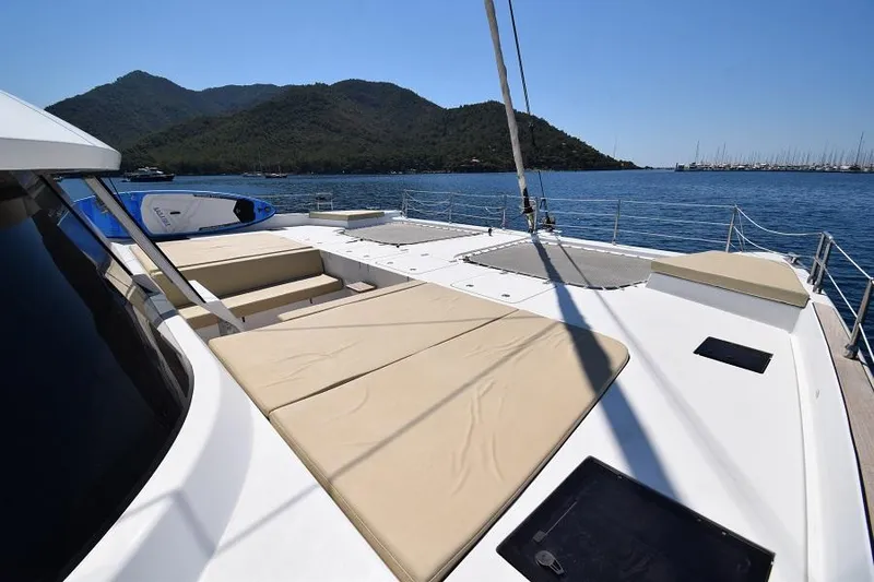Welcome Back Yacht Photos Pics Luxurious 2019 Sunreef 50 yacht deck with sunbeds, overlooking serene waters and distant mountains.