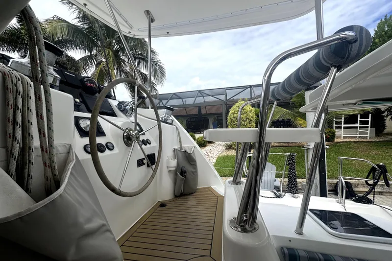  Yacht Photos Pics Helm of 2016 Leopard 44 catamaran with steering wheel and control panel, docked near palm trees.