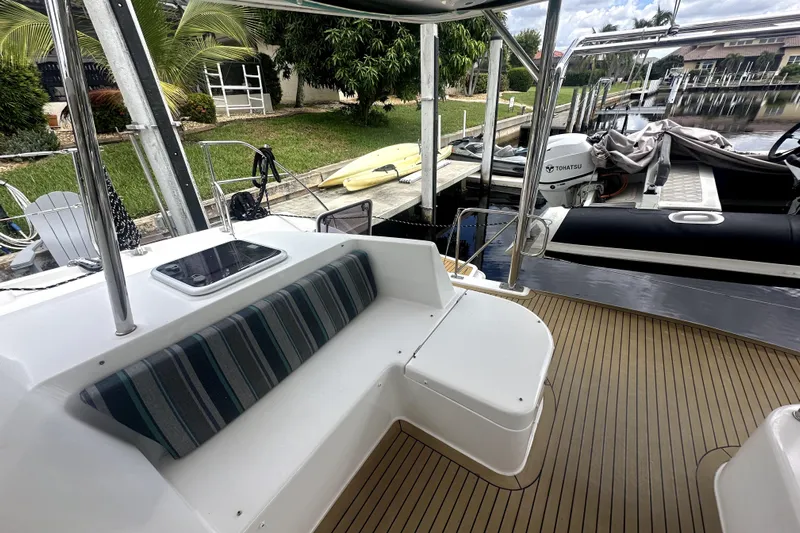  Yacht Photos Pics 2016 Leopard 44 yacht deck with seating, docked near lush greenery and a Tohatsu motor.