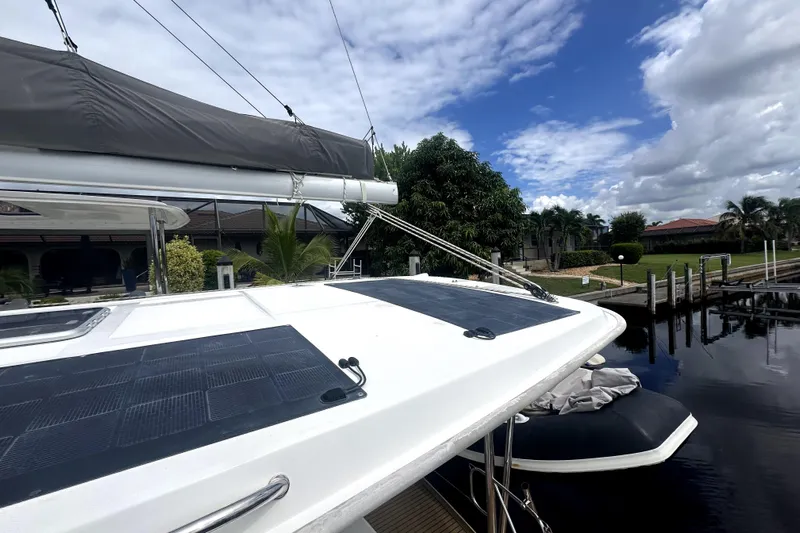  Yacht Photos Pics Leopard 44 catamaran docked, featuring solar panels and lush surroundings, under a partly cloudy sky.