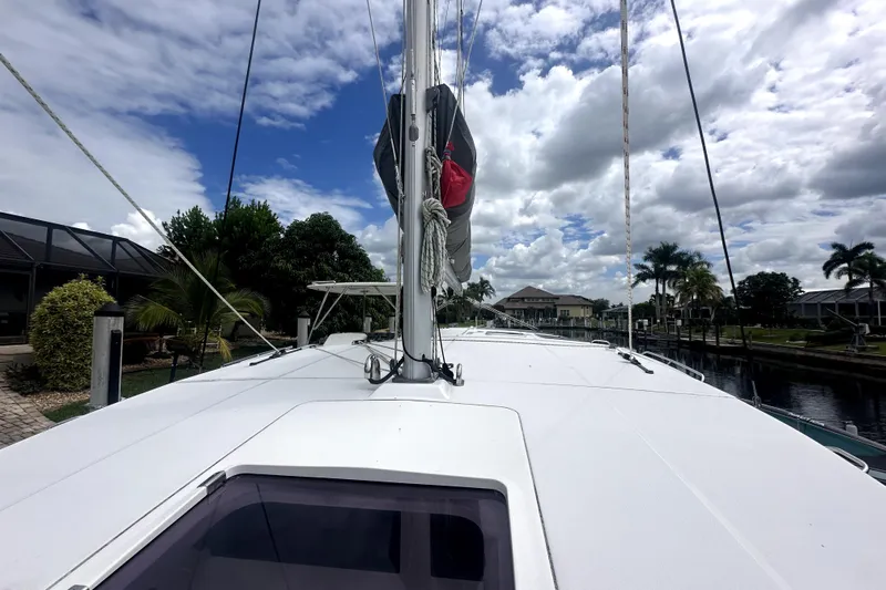  Yacht Photos Pics 2016 Leopard 44 catamaran docked under a partly cloudy sky, surrounded by lush greenery.