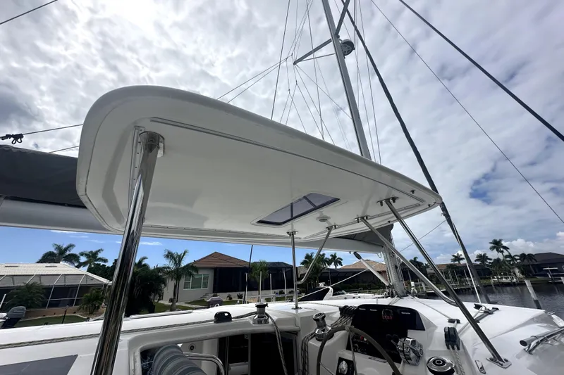  Yacht Photos Pics 2016 Leopard 44 catamaran cockpit with canopy, docked near waterfront homes under cloudy sky.