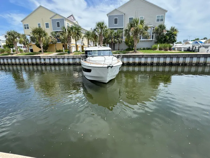  Yacht Photos Pics 2024 Beneteau Antares 11 docked near waterfront homes, surrounded by palm trees.