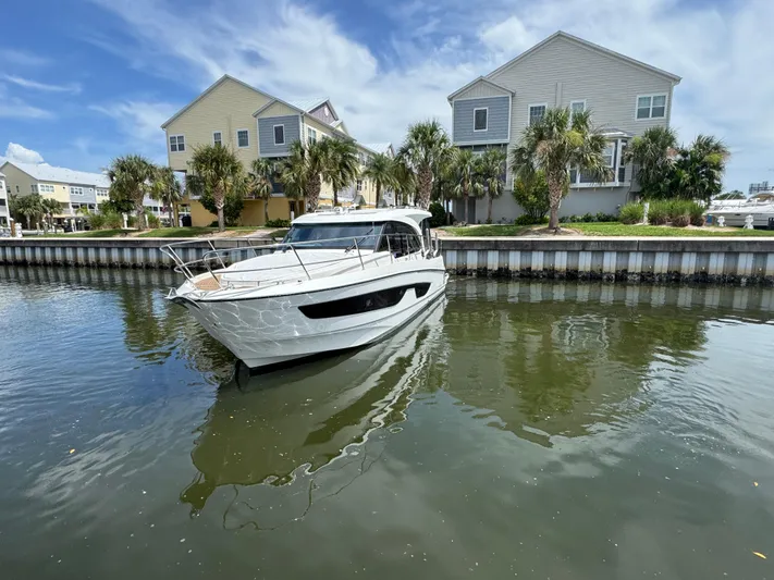  Yacht Photos Pics 2024 Beneteau Antares 11 boat docked near waterfront homes.