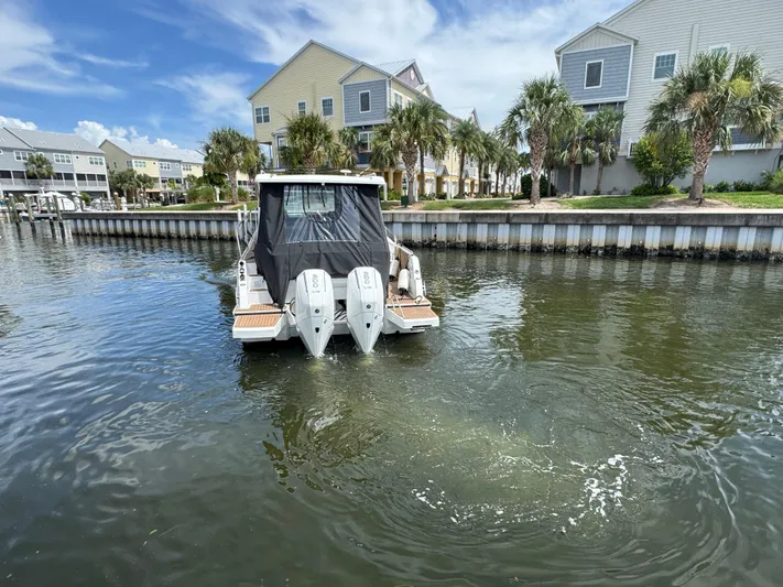  Yacht Photos Pics 2024 Beneteau Antares 11 boat docked near waterfront homes, featuring dual outboard engines.