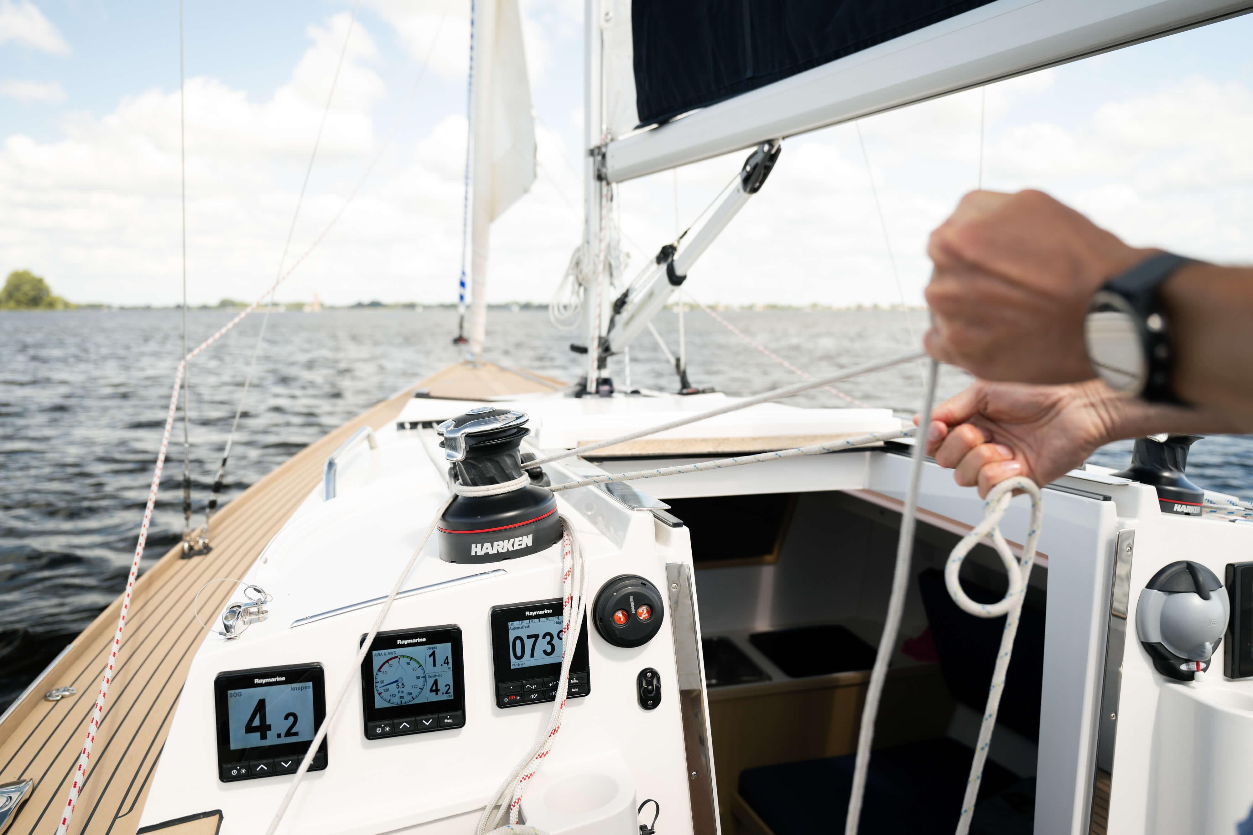 Sailing on a 2026 Saffier SC 8M Cabin, adjusting ropes, with digital displays visible.