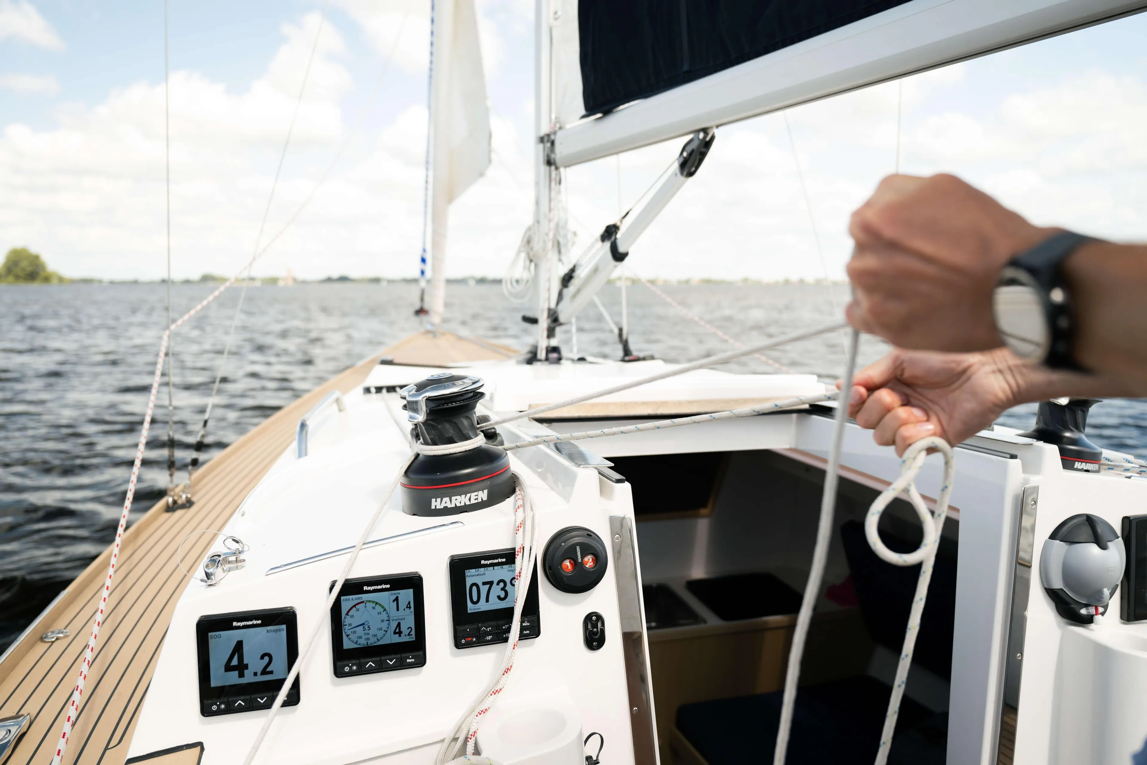 Sailing on a 2026 Saffier SC 8M Cabin, adjusting ropes, with digital displays visible.