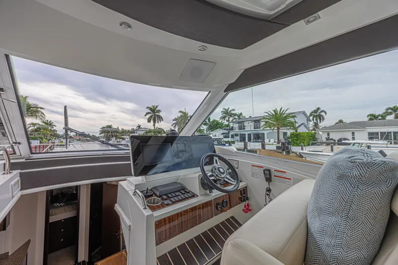 Low Hours!!! Yacht Photos Pics Interior view of 2012 Cruisers Yachts 48 Cantius helm with modern controls and waterfront backdrop.