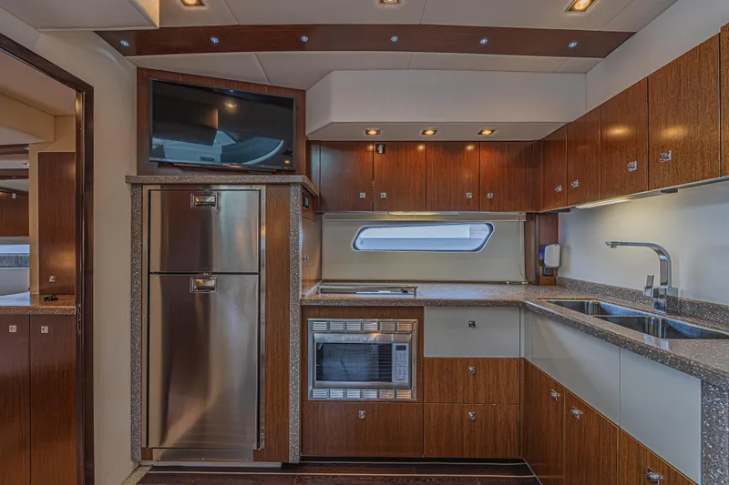 Low Hours!!! Yacht Photos Pics Luxurious 2012 Cruisers Yachts 48 Cantius kitchen with modern appliances and sleek wood cabinetry.