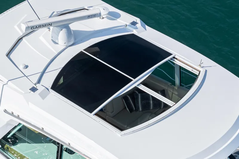 Serenity Yacht Photos Pics 2015 Cruisers Yachts 48 Cantius with open sunroof, featuring Garmin equipment, on clear water.