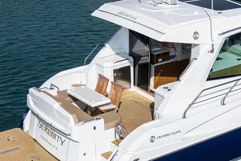 Serenity Yacht Photos Pics 2015 Cruisers Yachts 48 Cantius, luxury yacht with outdoor seating, docked on calm water.