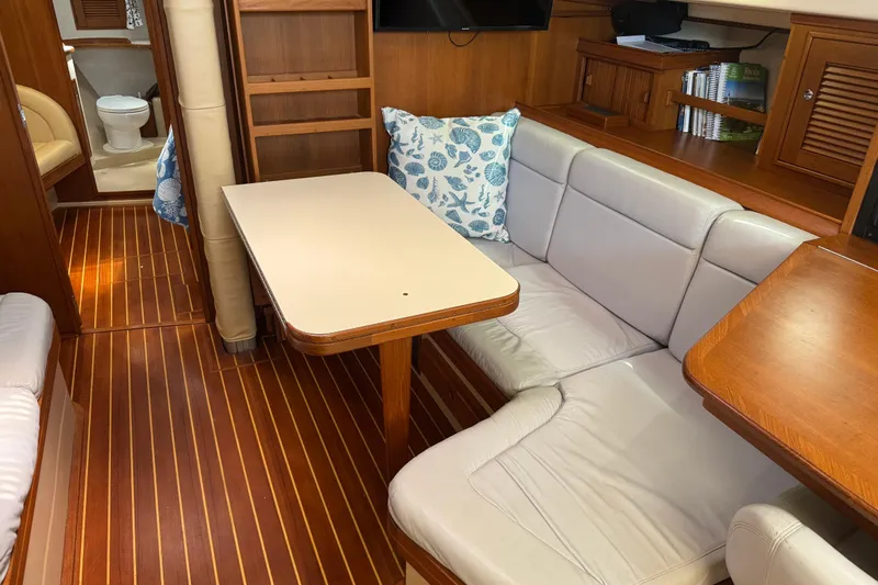 True North Yacht Photos Pics 2004 Island Packet 420 yacht interior with cozy seating, wooden flooring, and a compact dining area.