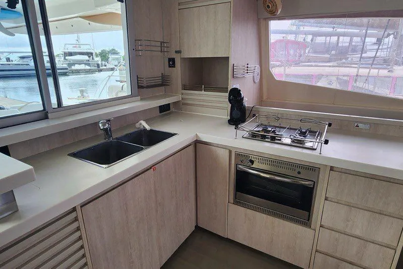 Jolly Dacha Yacht Photos Pics Modern kitchen in a 2015 Leopard 48 yacht with stove, sink, and marina view.