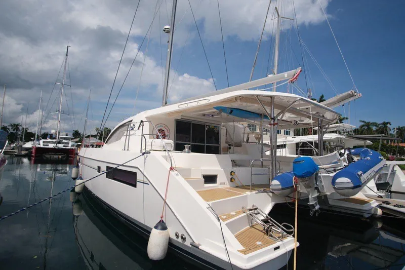 Jolly Dacha Yacht Photos Pics 2015 Leopard 48 yacht docked with inflatable boat, under a partly cloudy sky.