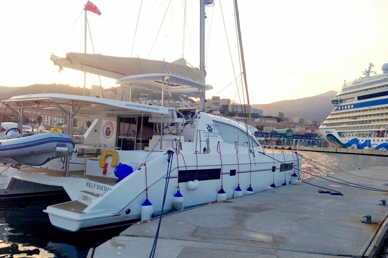 2015 Leopard 48 yacht docked at marina, sunset view, cruise ship in background.