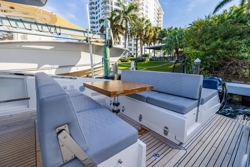  Yacht Photos Pics Astondoa 377 yacht deck with seating and table, 2023 model, docked near palm trees.