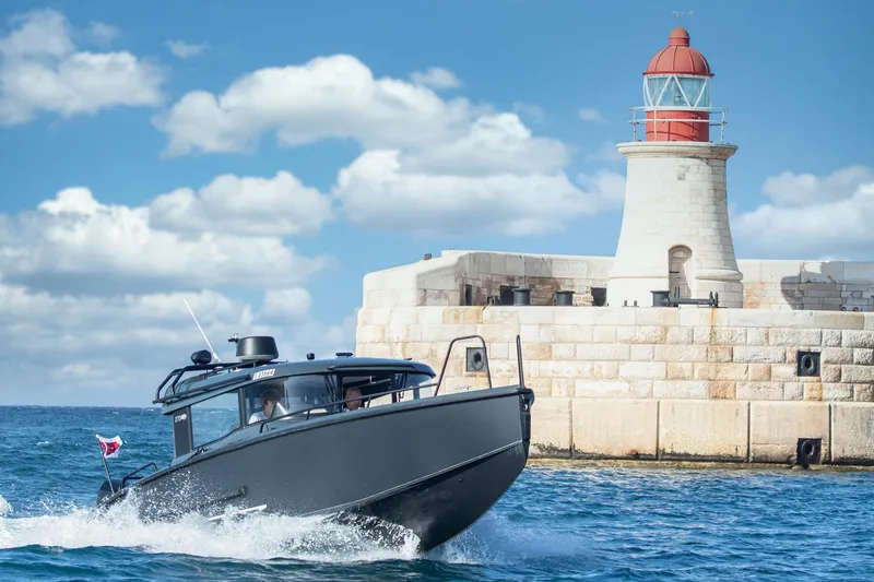  Yacht Photos Pics 2026 XO Boats EXPLR 10S PLUS cruising near a lighthouse on a sunny day.