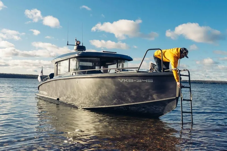  Yacht Photos Pics 2026 XO Boats EXPLR 10S PLUS on water, person in yellow jacket using ladder.