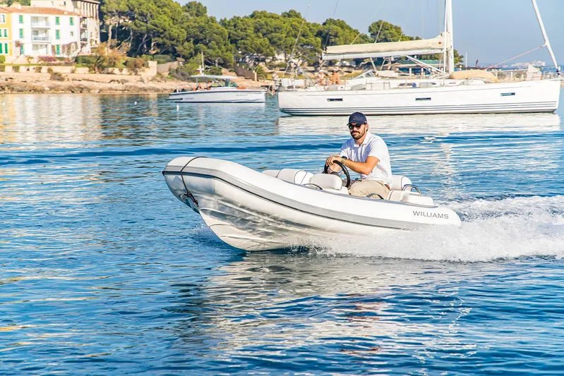  Yacht Photos Pics Man driving a Williams tender boat on calm water near a Prestige 680 yacht, 2016.