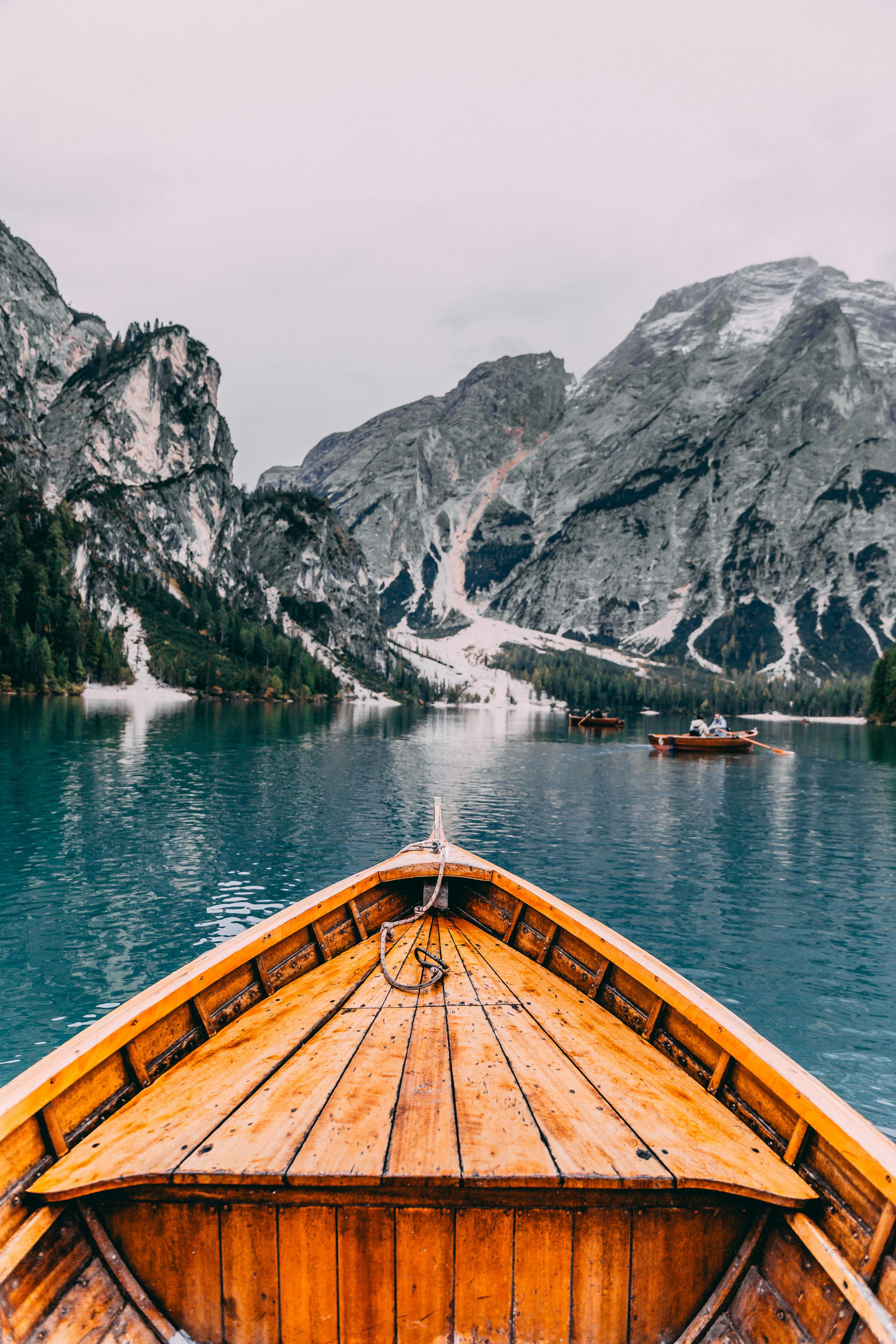 Wooden boat on serene lake with majestic mountain backdrop.