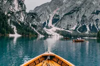 Wooden boat on serene lake with majestic mountain backdrop.