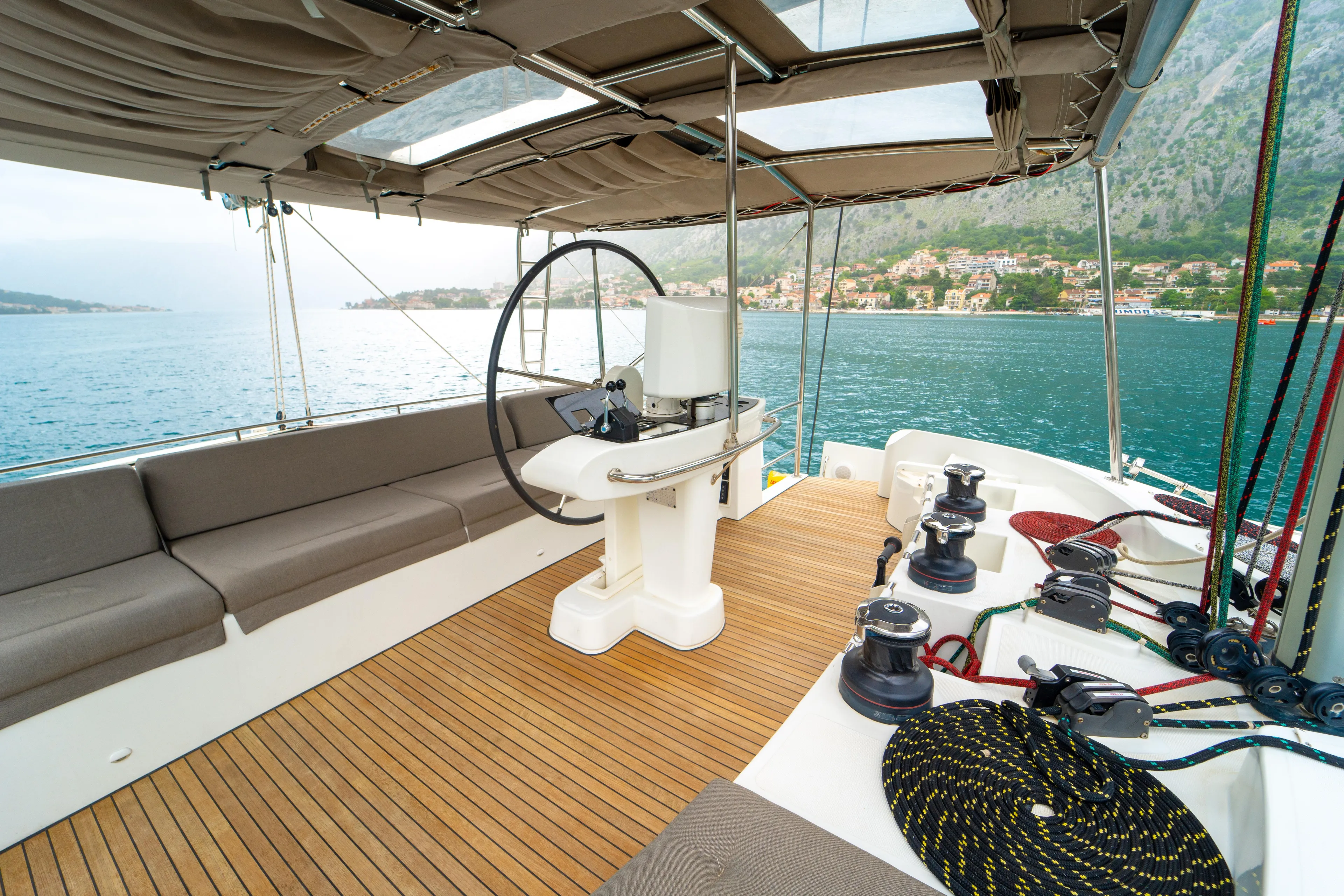  Yacht Photos Pics Luxurious 2015 Lagoon 52 F yacht deck with steering wheel and seating, overlooking scenic coastline.