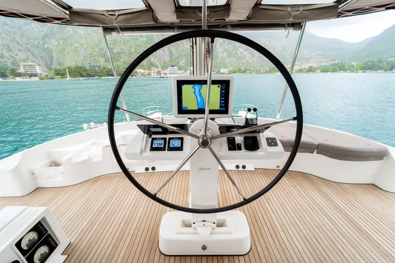  Yacht Photos Pics Steering wheel of 2015 Lagoon 52 F yacht with navigation display, docked by scenic mountains.