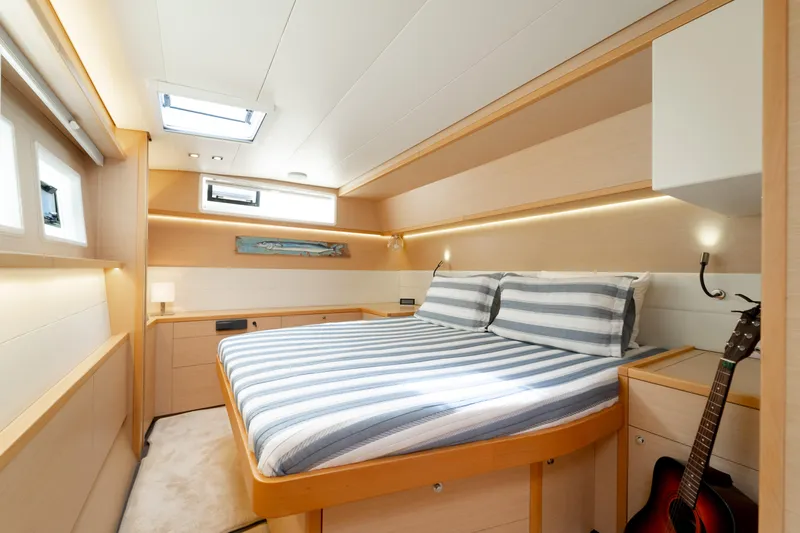  Yacht Photos Pics Luxurious cabin interior of 2015 Lagoon 52 F yacht with striped bedding and guitar.