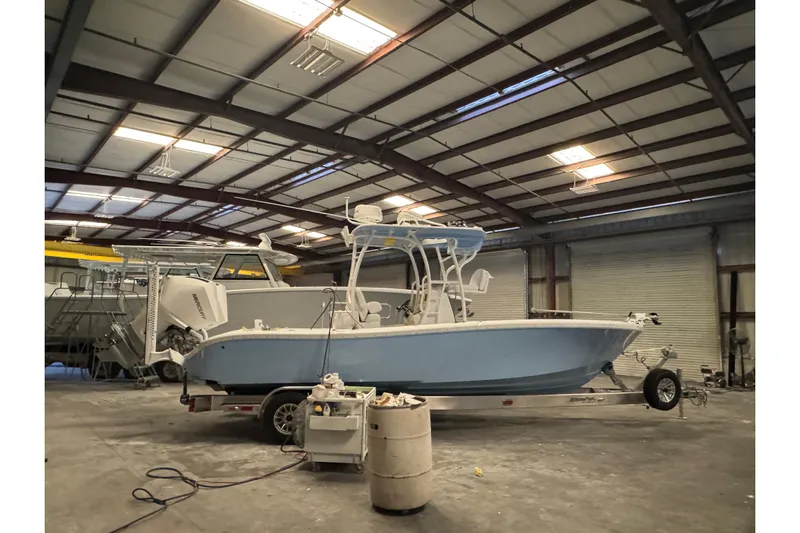  Yacht Photos Pics 2026 Yellowfin 26 Hybrid boat in a warehouse, on a trailer, under fluorescent lights.