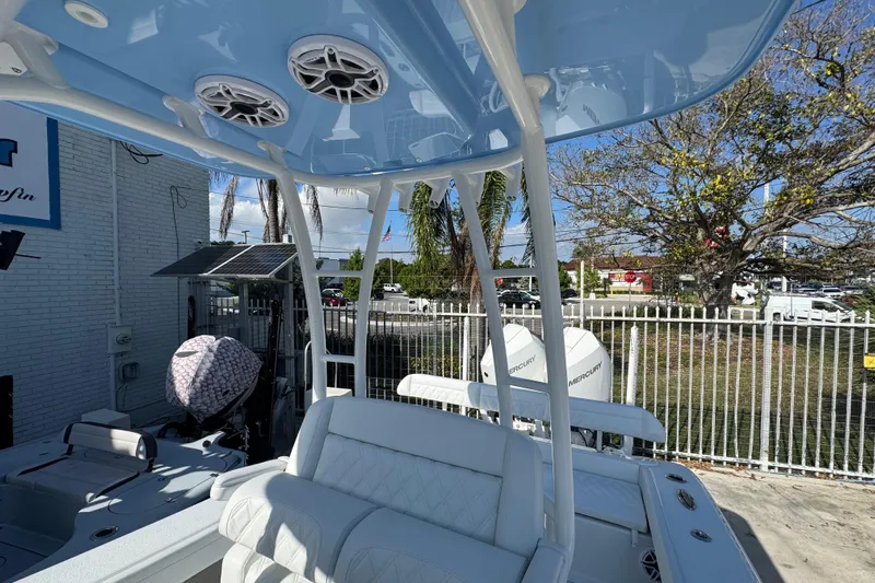  Yacht Photos Pics 2026 Yellowfin 26 Hybrid boat with blue canopy and white seating, parked outdoors.