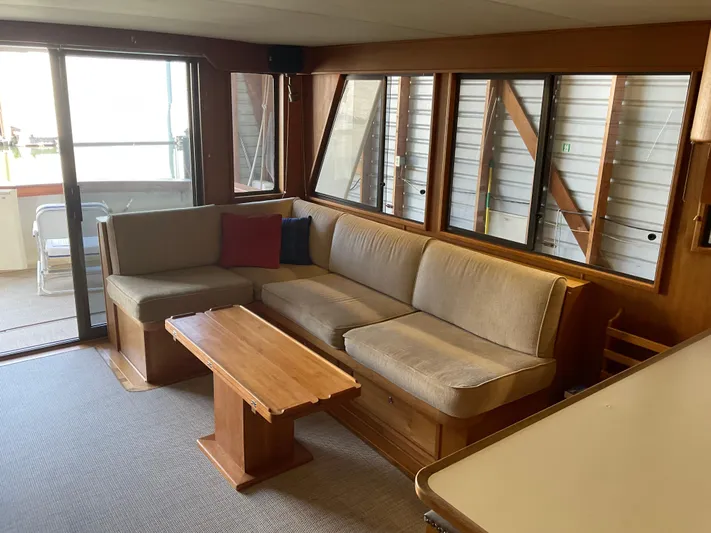  Yacht Photos Pics Interior of 1991 Nordic Pilothouse with beige sofa, wooden table, and large windows.