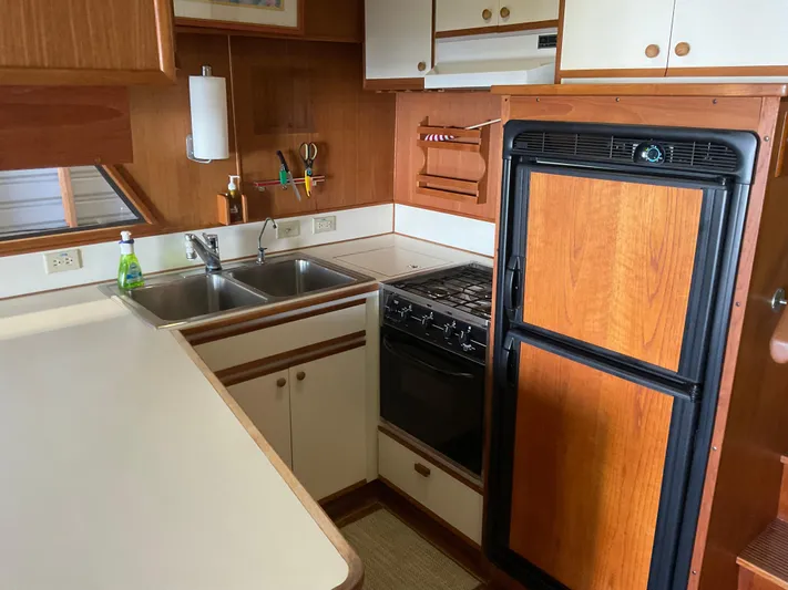  Yacht Photos Pics 1991 Nordic Pilothouse kitchen with wood cabinetry, dual sink, stove, and compact refrigerator.