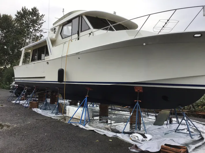  Yacht Photos Pics Nordic Pilothouse 1991 boat on stands, undergoing maintenance, surrounded by trees.