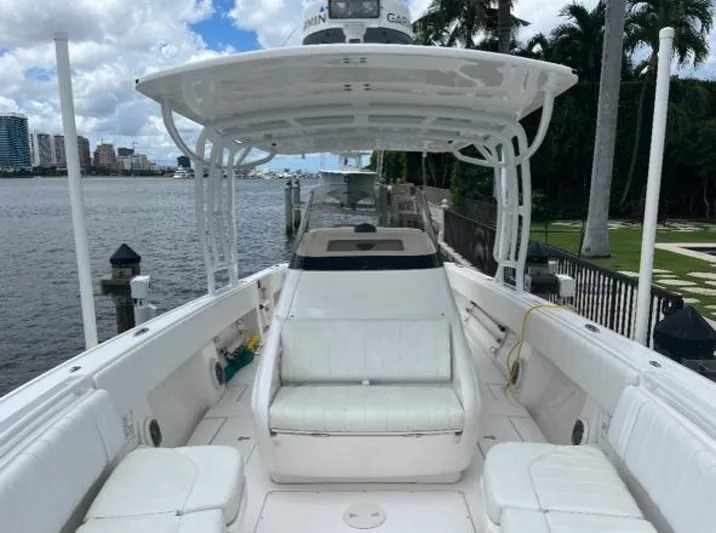 Gin Fizz Yacht Photos Pics 2012 Intrepid 327 boat with white seating, docked by a waterfront with palm trees.