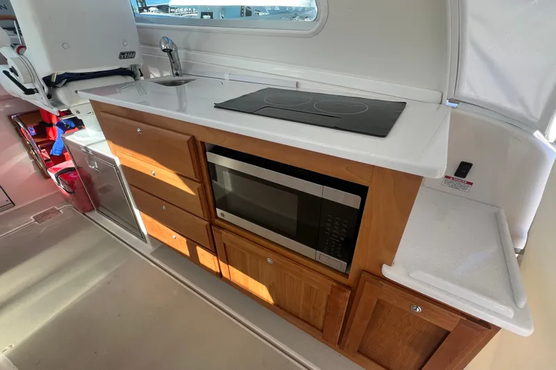  Yacht Photos Pics 2024 Back Cove 34O yacht kitchen with stove, microwave, and wooden cabinetry.