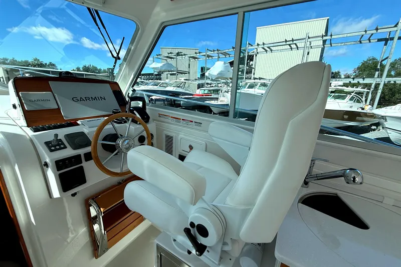  Yacht Photos Pics 2024 Back Cove 34O helm with Garmin navigation, white captain's chair, and wooden steering wheel.