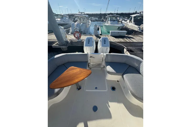  Yacht Photos Pics 2024 Back Cove 34O boat with cushioned seating and wooden table at marina.