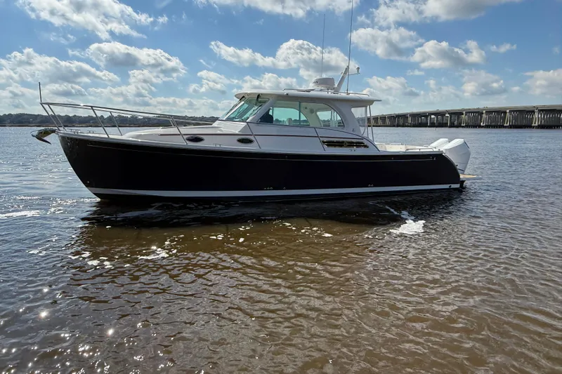  Yacht Photos Pics 2024 Back Cove 34O boat on calm water under a partly cloudy sky.