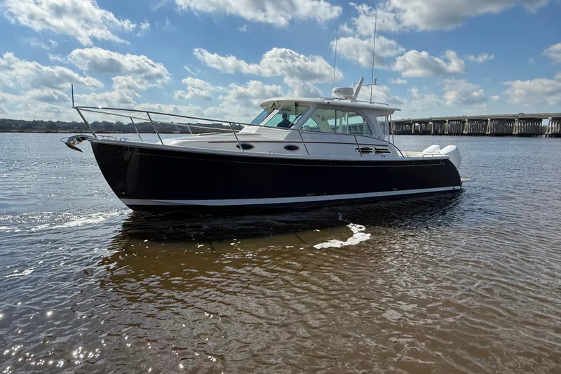  Yacht Photos Pics 2024 Back Cove 34O boat on calm water under a partly cloudy sky.