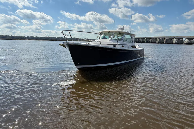  Yacht Photos Pics 2024 Back Cove 34O boat on calm water under a partly cloudy sky.