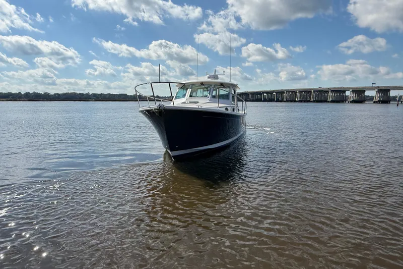  Yacht Photos Pics 2024 Back Cove 34O boat cruising on a sunny day with a bridge in the background.