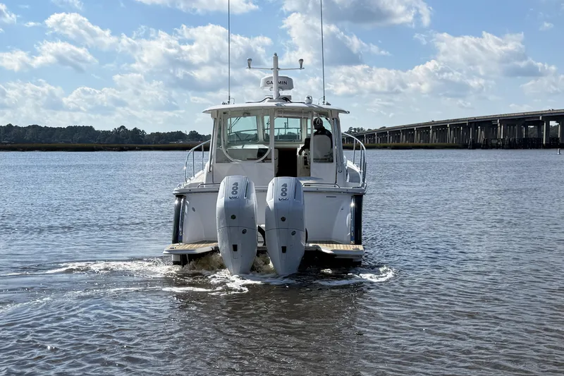  Yacht Photos Pics 2024 Back Cove 34O boat cruising on a sunny day with bridge in background.