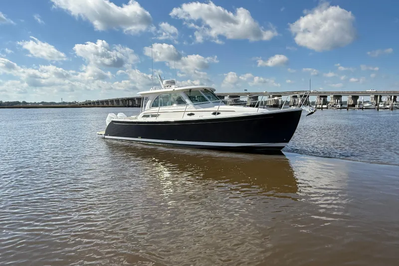  Yacht Photos Pics 2024 Back Cove 34O boat on calm water under a blue sky with clouds.