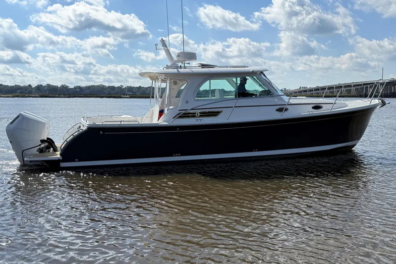  Yacht Photos Pics 2024 Back Cove 34O boat on calm water under a partly cloudy sky.