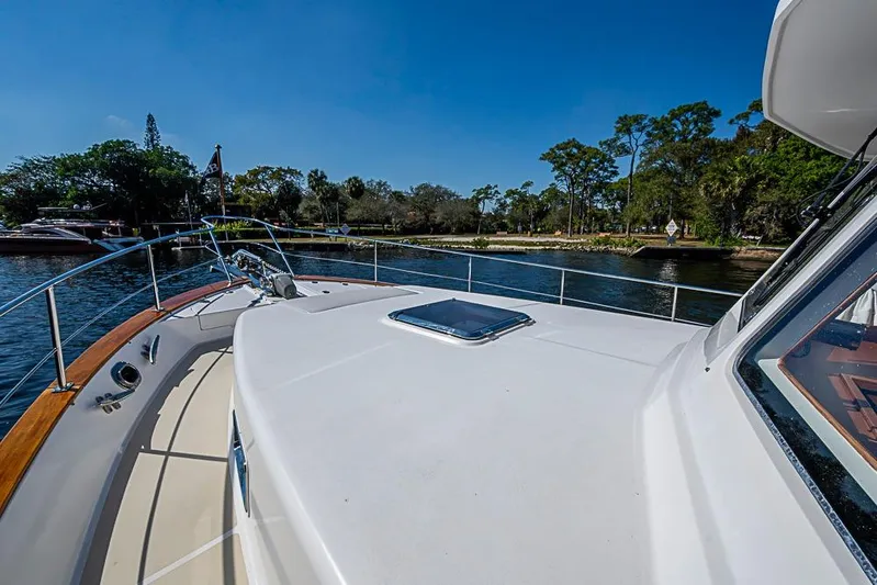 Hayride Yacht Photos Pics 2013 Grand Banks 43 Europa yacht on calm water, surrounded by lush greenery.