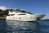 Luxurious 2004 Custom Line 94 yacht on serene blue waters near rocky shoreline.