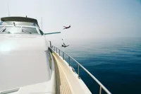 Two people diving off a Custom Line 94 yacht into the ocean, 2004 model.