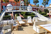 Luxurious 2004 Custom Line 94 yacht deck with seating, surrounded by palm trees and colorful buildings.
