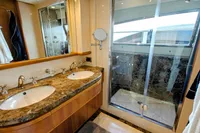 Luxurious yacht bathroom with dual sinks, marble countertop, and glass shower in Custom Line 94, 2004.